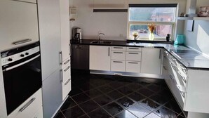 A modern kitchen with white cabinets, a black countertop, and a window with a view of the outside. - 5 Star Holiday Home in Galten (Galten)