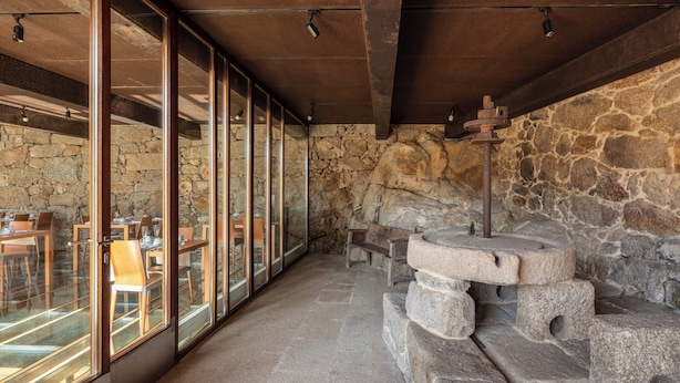 Um restaurante com paredes de pedra, mesas de madeira e janelas grandes.