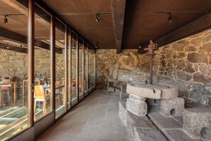 A restaurant with stone walls, wooden tables, and large windows. - A CASA DE ALDÁN (Cangas)
