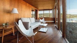 Uma sala de estar moderna com interior em madeira, um sofá branco, uma mesa de centro e uma luminária.