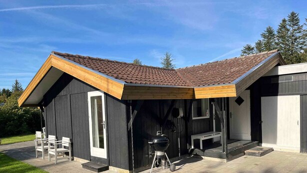 Eine kleine, dunkle Holzhütte mit geneigtem Dach und einer Veranda.