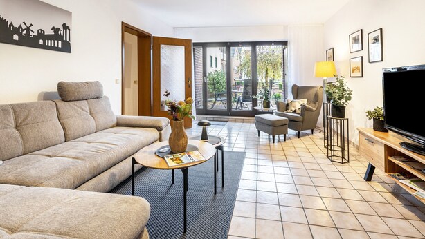 Ein modernes Wohnzimmer mit einer Couch, einem Couchtisch, einem Fernseher und einem Essbereich mit Stühlen.