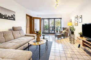 Un soggiorno moderno con un divano, un tavolino, una televisione e un'area pranzo con sedie.