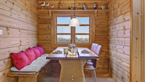 A wooden cabin with a dining table, bench seating, and a window with a view. - 5 Star Holiday Home in Glesborg (Glesborg)