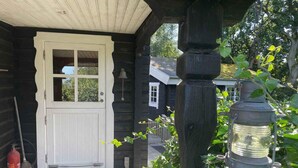 A wooden cabin with a white door, a bell, and a lantern on the porch. - 5 Star Holiday Home in Glesborg (Glesborg)