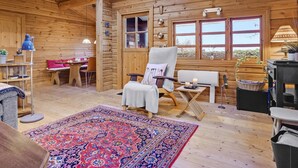 A cozy log cabin interior with a high ceiling, a large window, a comfortable seating area, and a dining space. - 5 Star Holiday Home in Glesborg (Glesborg)