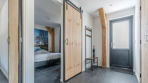 Une chambre moderne avec un lit, une armoire en bois et une porte donnant sur une autre pièce.