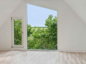 Una habitación con un amplio ventanal corredera que da a un paisaje verde.