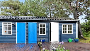 Et blåt hus med træterrasse, to blå døre og vinduer.