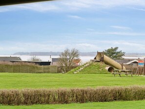 A grassy field with a playground featuring a slide and a picnic table. - 5 Star Holiday Home in Assens (Assens)