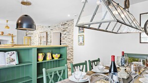 A dining area with a stone wall, a green buffet, and a chandelier. - Stylish luxurious 5 bedroom house, central Lynton (Lynton)