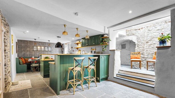 A modern kitchen with green cabinets, a central island with bar stools, and pendant lighting. - Stylish luxurious 5 bedroom house, central Lynton (Lynton)