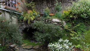 A stone archway surrounded by lush greenery and flowering plants. - Stylish luxurious 5 bedroom house, central Lynton (Lynton)