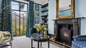 A living room with a fireplace, a large mirror, and a view of the outside. - Stylish luxurious 5 bedroom house, central Lynton (Lynton)
