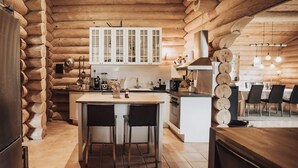 A log cabin kitchen with a central island, white cabinets, and a dining area with chairs. - 5 Star Holiday Home in Jaegerspris (Jægerspris)