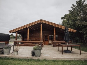 A log cabin with a porch, outdoor seating, and potted plants. - 5 Star Holiday Home in Jaegerspris (Jægerspris)