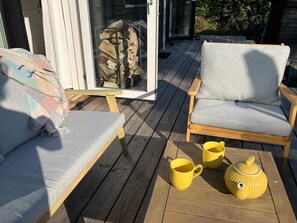 A wooden deck with two grey upholstered chairs, a yellow teapot, and two yellow mugs. - 5 Star Holiday Home in Vejby (Vejby)