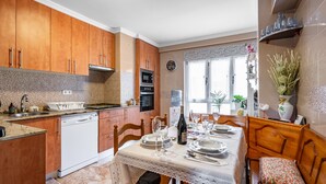 A kitchen with wooden cabinets, a dishwasher, and a dining area with a table set for two.