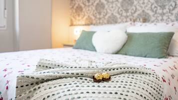 Una cama bien hecha con una colcha estampada, dos almohadas y un adorno sobre la cama.