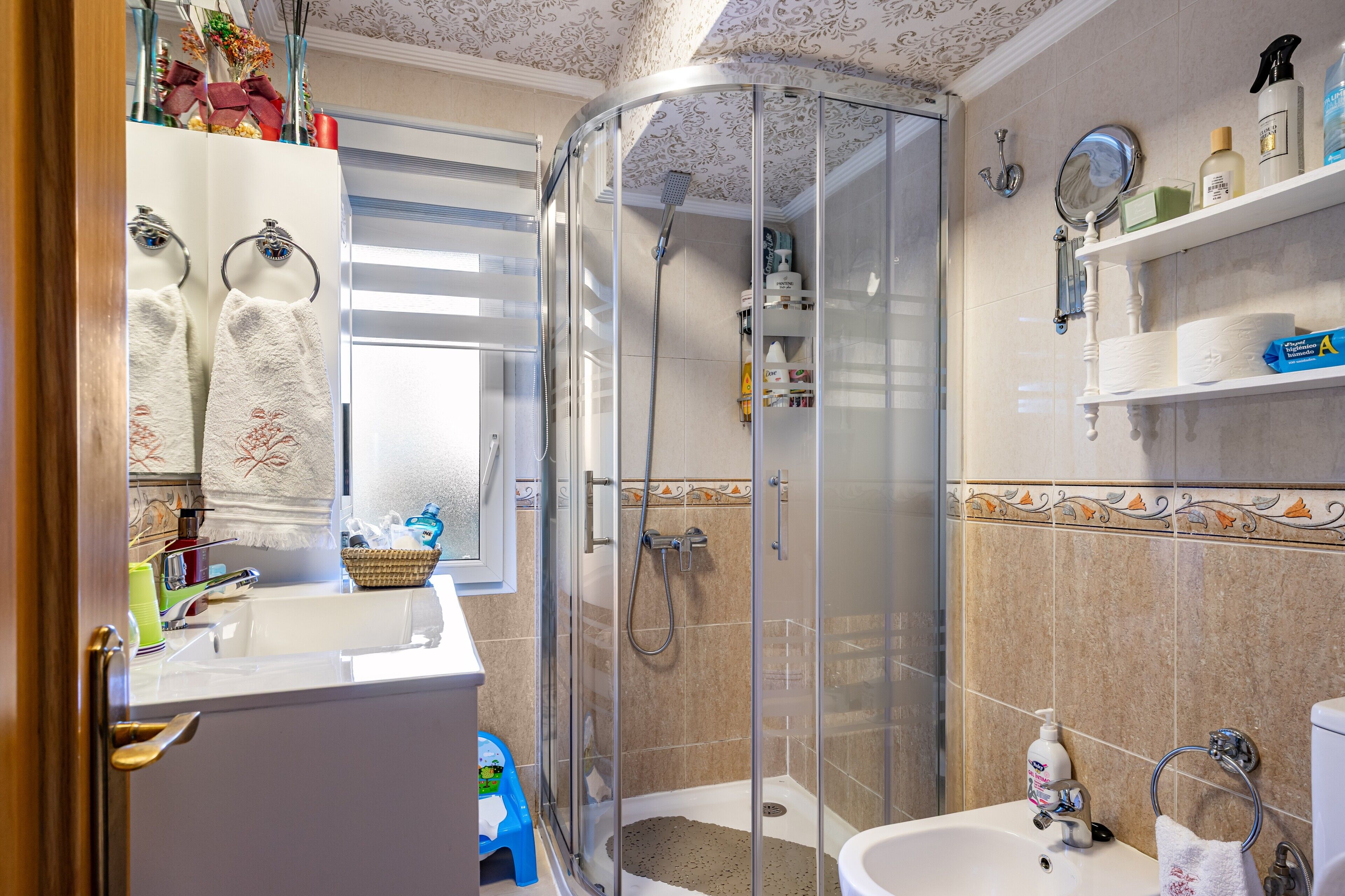 Un baño con ducha de vidrio, lavabo e inodoro.