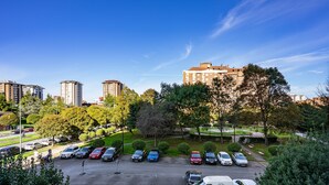 A parking lot with multiple cars and a white van, surrounded by trees and buildings.