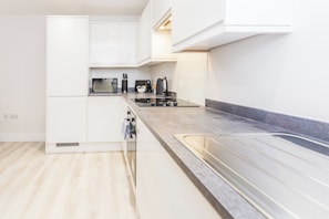 Een moderne keuken met witte kasten, een roestvrijstalen spoelbak en een inbouwoven.