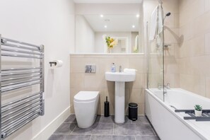 Une salle de bain moderne avec une douche à parois de verre, un lavabo blanc et des toilettes.