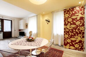 A dining area with a round table, chairs, a television, and a decorative wall piece.