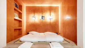 A room with a wooden wall, a bed with white bedding, and a shelf with books. - Apartment 'Bilocale 10' with Mountain View, Balcony and Wi-Fi (Gressan)