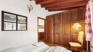 Un dormitorio con cama, una silla, un armario y un espejo.