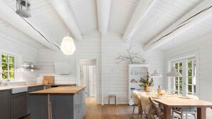 Een moderne keuken met witte houten wanden, een centraal eiland en een eethoek met een houten tafel en stoelen.