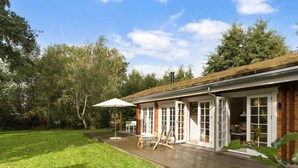 Een huis met een houten terras, een overdekte patio en een gazon.