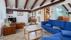 A living room with a blue sofa, wooden table, and a television. - Apartment 'Trilocale 13' with Mountain View and Wi-Fi (Gressan)