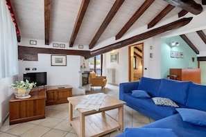 A living room with a blue sofa, wooden table, and a television.