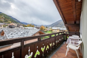 A balcony with a wooden railing, a small table, and a chair.