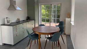 Eine moderne Küche mit Essbereich, großen Fenstern und Blick auf Grünflächen.