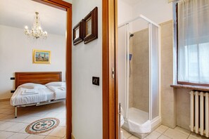 Un dormitorio con cama, ducha y ventana con cortinas.