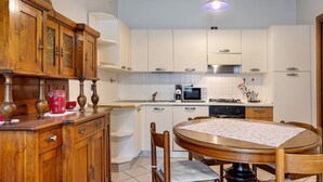 Een keuken met witte kastjes, een houten eettafel en een hangende吊灯.