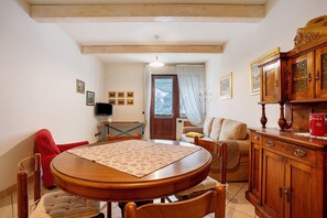 A dining area with a round wooden table, chairs, a sofa, and a wooden cabinet with drawers.