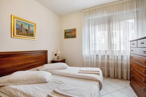 A hotel room with a wooden headboard, two beds, a dresser, and two paintings on the wall.