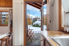 An open door leading to a snowy outdoor area with a dining table and chairs inside.