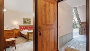 A wooden door leading to a bedroom with a bed, a nightstand, a chair, and a painting on the wall. - Apartment 'Bilocale 4' with Mountain View, Shared Terrace, and Wi-Fi (Gressan)