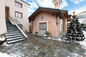 Un bâtiment avec un escalier, une porte en bois et un sol recouvert de neige.