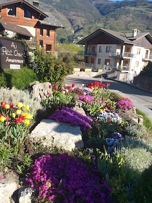 A residential area with a sign for 'Au Petite Chemin Apartments' and a view of a mountain range.