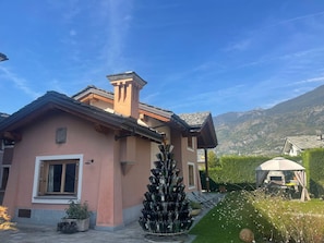 A house with a chimney, a window, and a garden with a barbecue area.