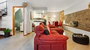A modern living room with a sofa, a dining area, a kitchen, and a staircase. - Welcome to Your Home Away from Home with Sea View! (Funchal)