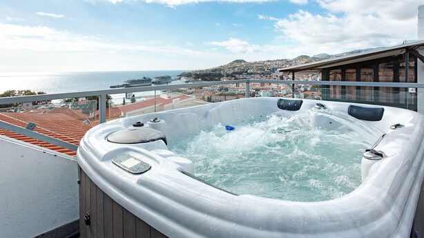 A hot tub on a balcony with a view of the sea and a cityscape. - Welcome to Your Home Away from Home with Sea View! (Funchal)