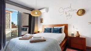 A bedroom with a bed, a nightstand, a wall-mounted air conditioner, and a view through a glass door. - Welcome to Your Home Away from Home with Sea View! (Funchal)