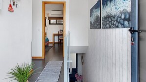 A hallway with a striped rug, a plant, and a painting of waves on the wall. - Welcome to Your Home Away from Home with Sea View! (Funchal)