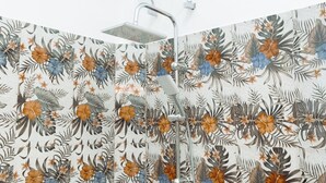 Eine Dusche mit blumenmuster-verzihelter Wand, einer Handbrause und einem fest installierten Bedienfeld.